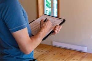 A close up view on the arm of a professional man wearing a short sleeved blue shirt, filling out papers during a building survey